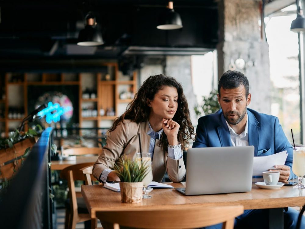 business-colleagues-using-laptop-and-analyzing-documents-on-a-meeting-in-cafe-.jpg